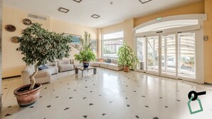 A spacious lobby with a large potted tree, a sofa, and a coffee table.