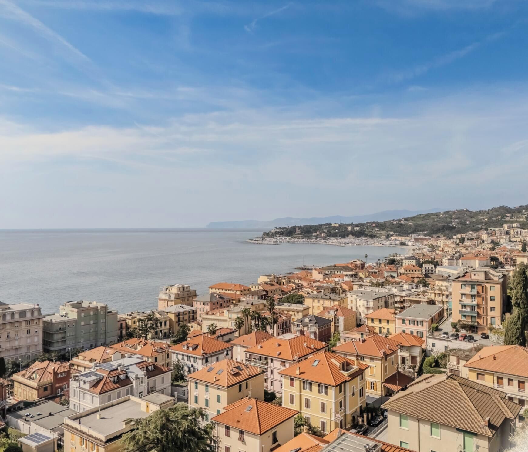 Eine Küstenstadtlandschaft mit dichter Bebauung, klarem Himmel und Blick auf das Meer.