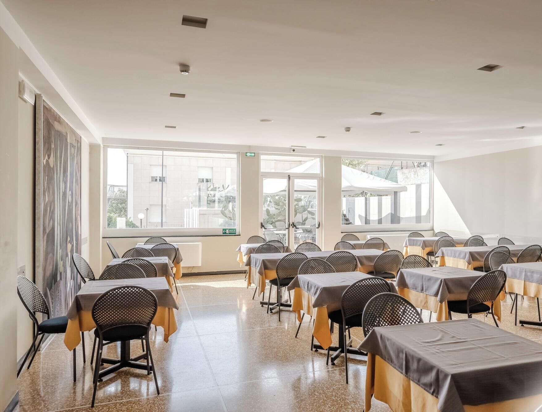 Une salle de conférence dotée de plusieurs tables et chaises, de grandes fenêtres et offrant une vue sur l’extérieur.