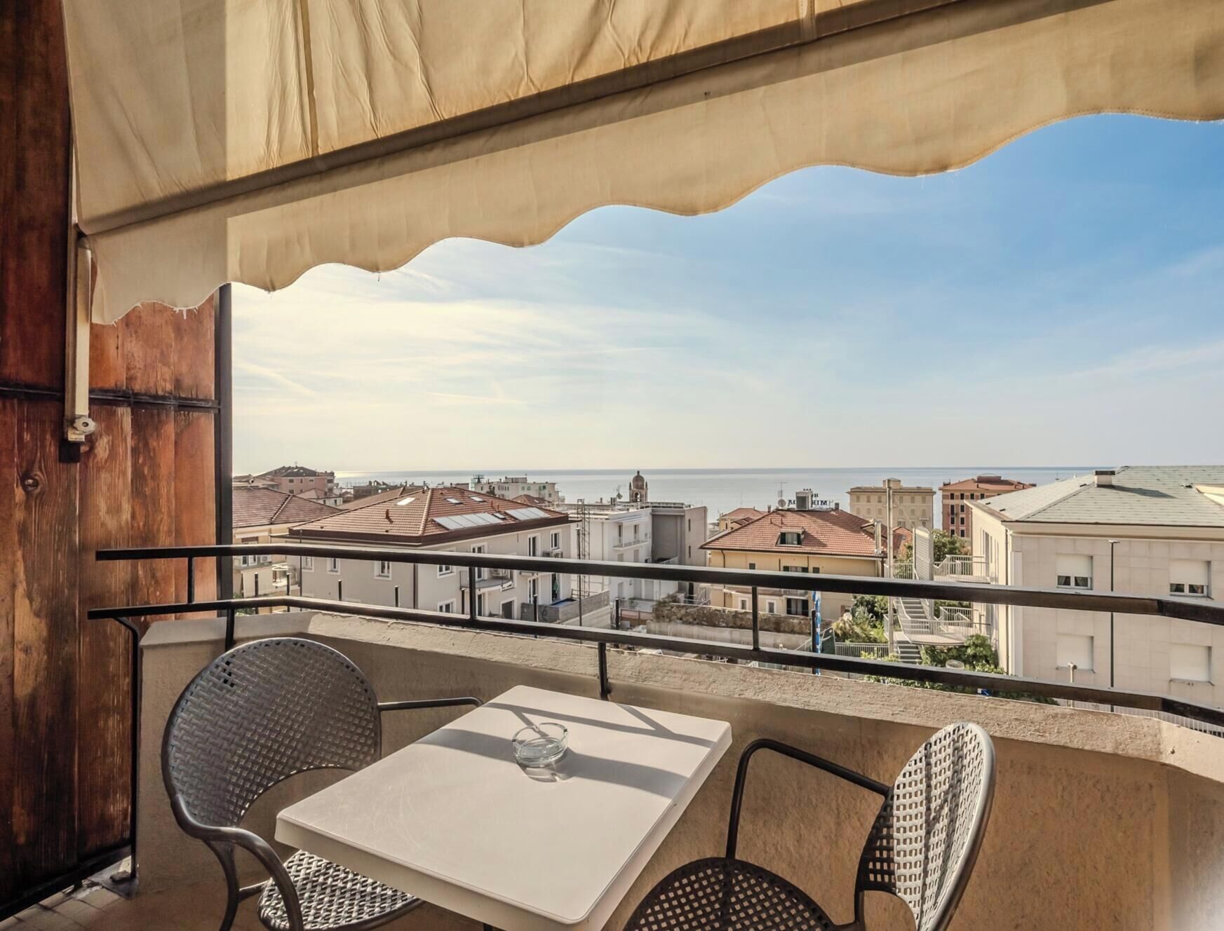 Ein Balkon mit Tisch und Stühlen mit Blick auf eine Küstenstadt.