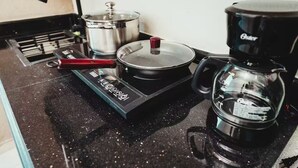 Una cocina con estufa, una olla, cafetera y un termómetro.