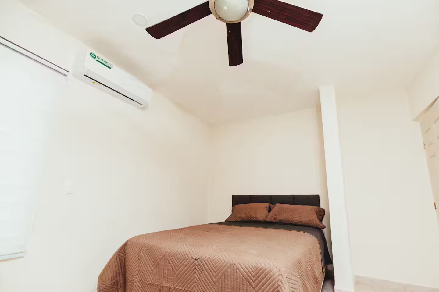 Une chambre à coucher avec un lit, un ventilateur de plafond et un appareil de climatisation.