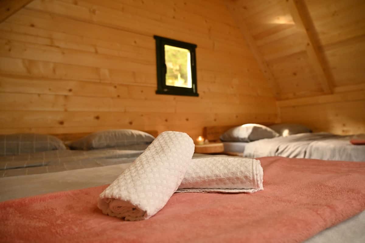 Un dormitorio rústico de madera con cama, almohadas y un ventanal.