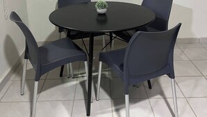 A round table with four chairs, a small potted plant, and a white wall. - Apartments cabos 6 (San José del Cabo)