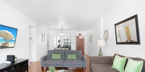 A living room with a sofa, a television, and a dining area in the background. - Tides Great condo on the beach! Big promotions (Hollywood)