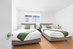 A hotel room with two beds, a window with a city view, a tray with a bottle and glasses, and a door with a handle. - Beautiful APT w/ Ocean View and Beach Access (Hollywood)