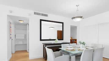 Un coin repas avec une table dressée pour quatre personnes, un grand miroir au-dessus de la table et un luminaire au plafond.