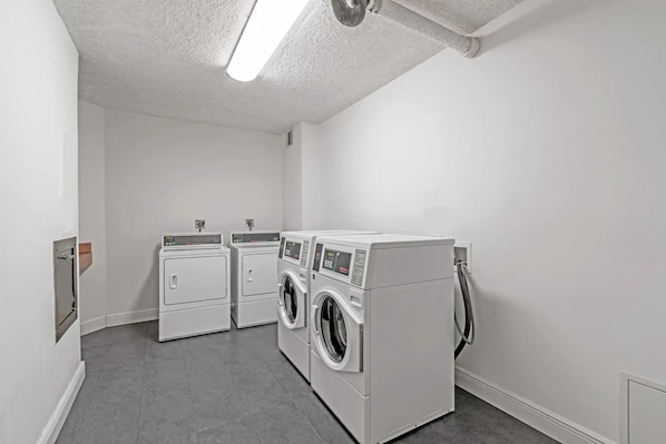 Een wasserette met twee drogers en twee wasmachines, een fluorescent lamp en een stopcontact op de muur.