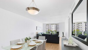 Een moderne eetruimte met een glazen tafel, witte borden en een hangende lamp.