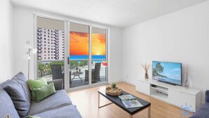 Een moderne woonkamer met een bank, een salontafel en een televisie op een witte kast.
