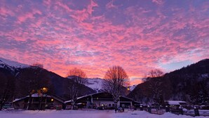 A hotel with a mountain backdrop, snow-covered surroundings, and a clear sky.