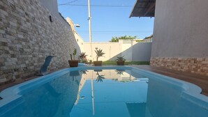 A swimming pool with a clear blue water surface, surrounded by walls with a brick pattern on one side and a plain wall on the other. - Swimming pool, leisure and fun in Cabo Frio. (Bairro Nova Califórnia Cabo Frio)