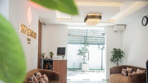 Eine moderne Hotelhalle mit einer Rezeption, zwei Sofas und einem großen Fenster mit Blick auf die Straße.