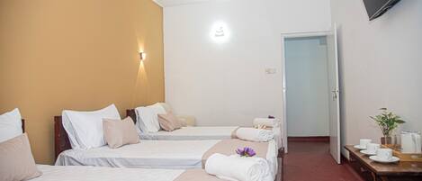 Habitación de hotel con dos camas, un escritorio con silla, un televisor y una puerta que da a otra habitación.