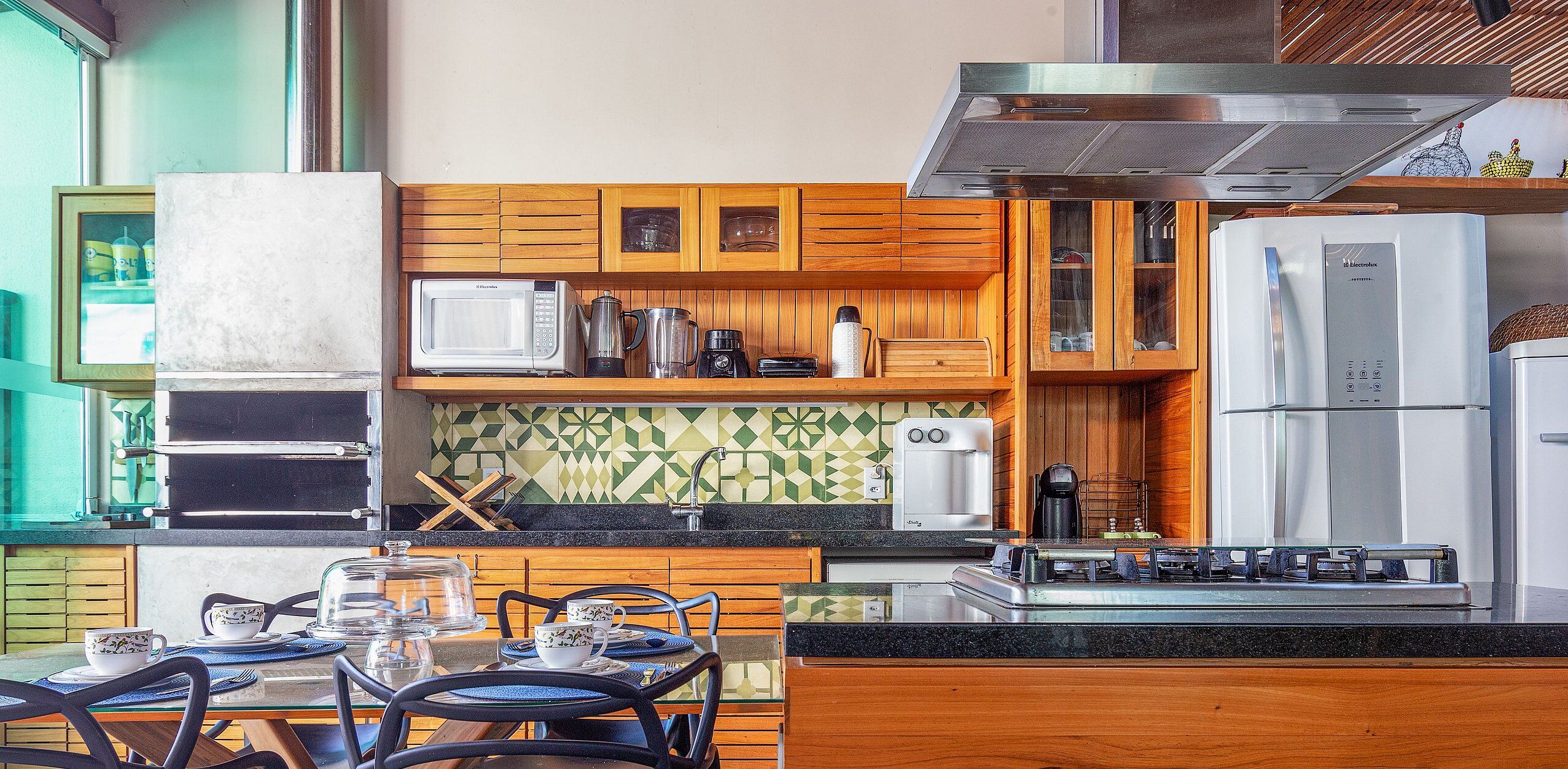 A compact kitchen with wooden cabinets, a microwave, a coffee maker, and a refrigerator.