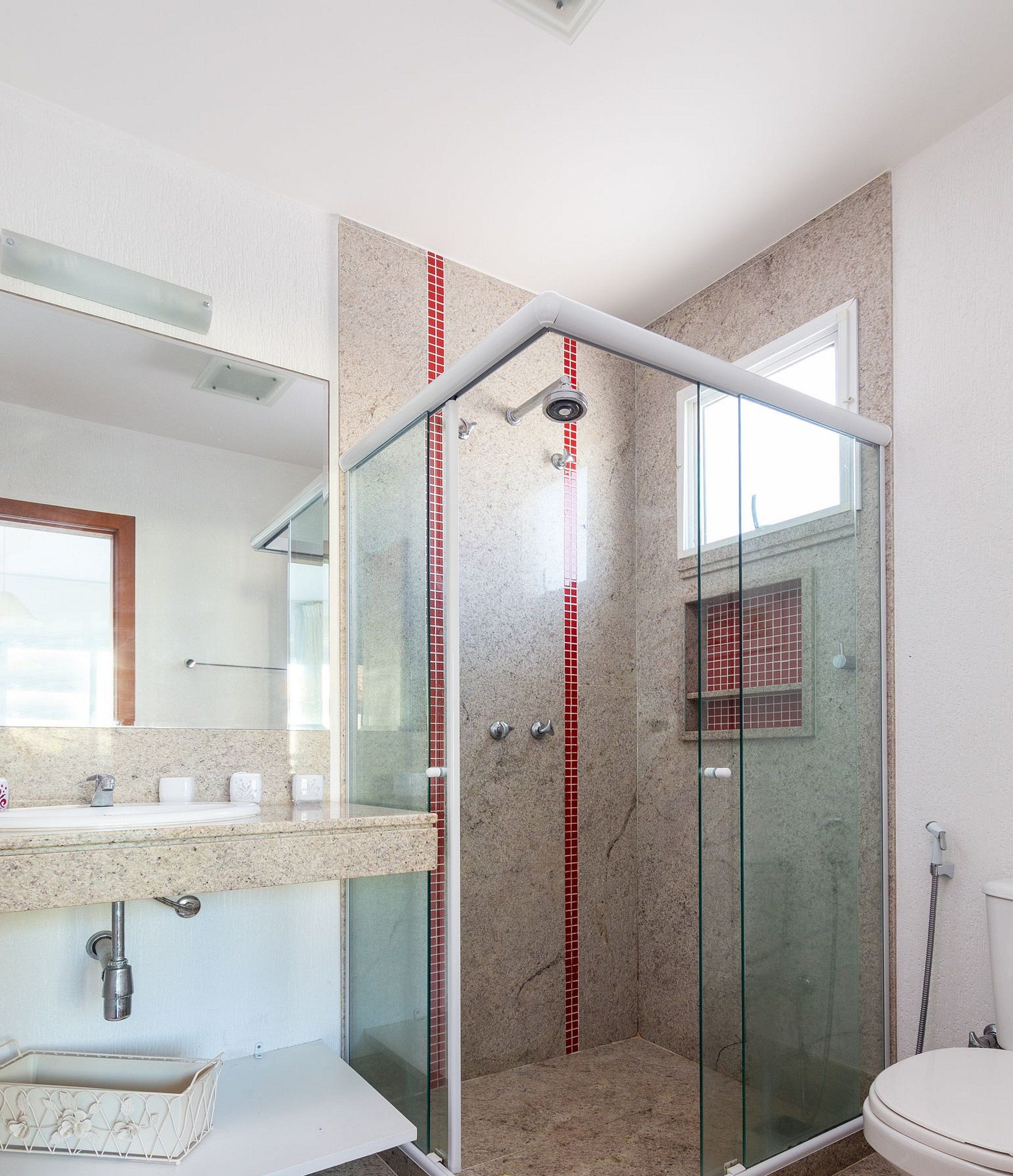 Une salle de bain moderne avec une douche à parois de verre, un lavabo doté d’un plan de travail en marbre et des toilettes.