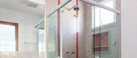 Une salle de bain moderne avec une douche à parois de verre, un lavabo doté d’un plan de travail en marbre et des toilettes.