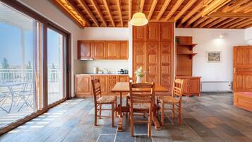 A spacious kitchen with wooden cabinets, a dining table with chairs, and a large window with a view of the outdoors.