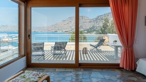 A balcony with a view of the sea and mountains, furnished with chairs and a table. - Arte Pefki Beachfront Suites (Rhodes)