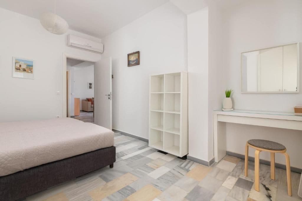 A bedroom with a bed, a desk with a chair, a wardrobe, and a mirror.