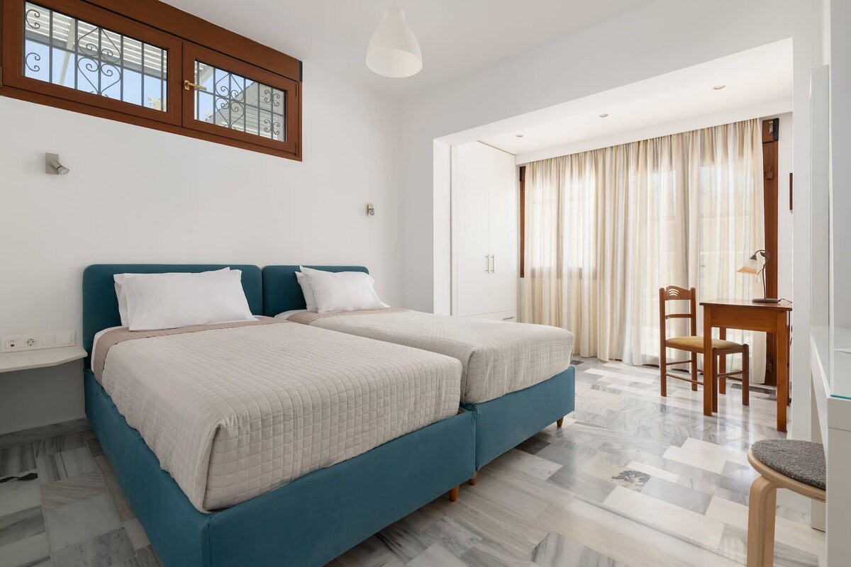 A hotel room with two beds, a desk, and a chair.