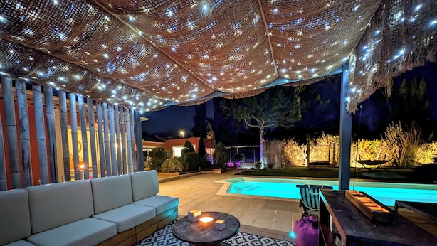 An outdoor patio area with a pool, seating, and string lights.