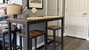 A room with a dark wooden table and chairs, a lamp, a framed picture, and a white door. - Spacious little condo at SML- Mariner's Landing Resort (Huddleston)