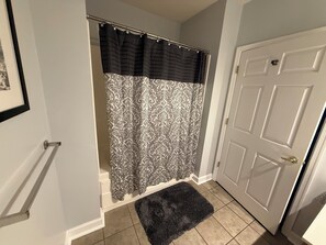 A bathroom with a shower curtain, a door, and a rug. - Spacious little condo at SML- Mariner's Landing Resort (Huddleston)