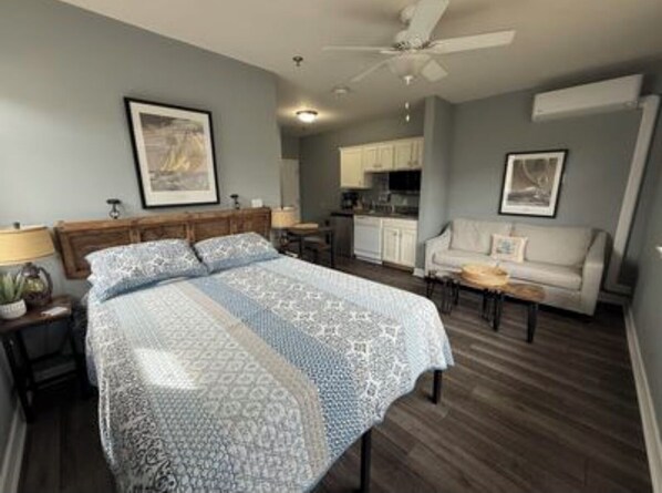 A bedroom with a large bed, a ceiling fan, a kitchenette, and a seating area with a sofa and a coffee table. - Spacious little condo at SML- Mariner's Landing Resort (Huddleston)