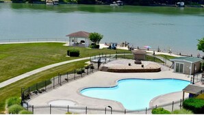 A swimming pool with a surrounding deck, a gazebo, and a small building near a lake. - Spacious little condo at SML- Mariner's Landing Resort (Huddleston)