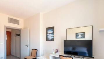 Habitación de hotel con cama, televisor, una silla y obras de arte en la pared.