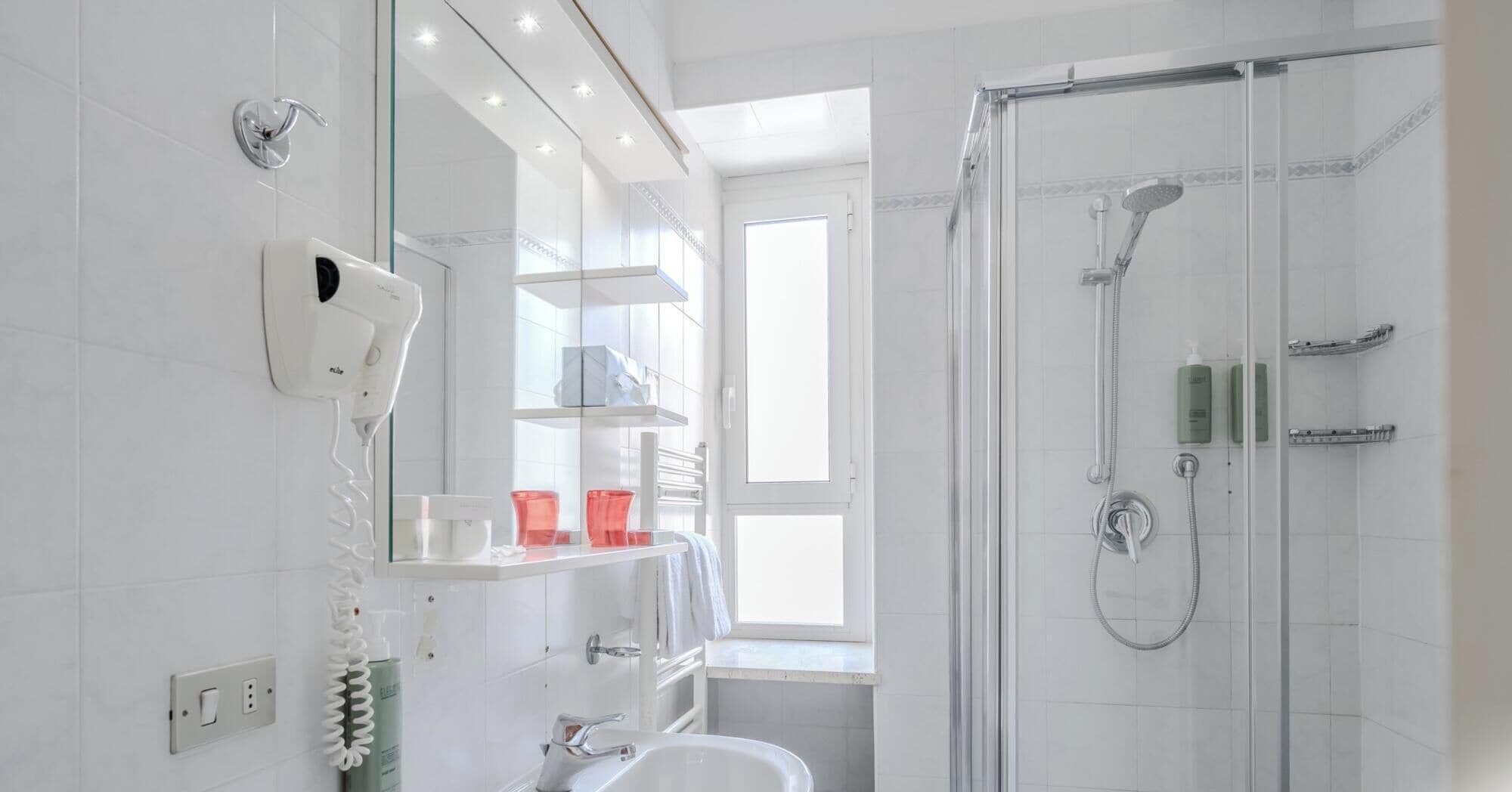 A modern bathroom with a glass shower enclosure, a white sink, and a mirror above the sink.