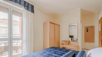 Ein Hotelzimmer mit Bett, Schrank, Schreibtisch mit Spiegel und Fenster mit Ausblick.
