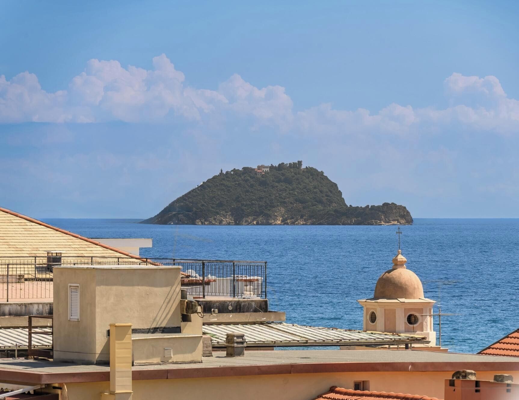 A coastal view with a building featuring a rooftop terrace and a dome structure.