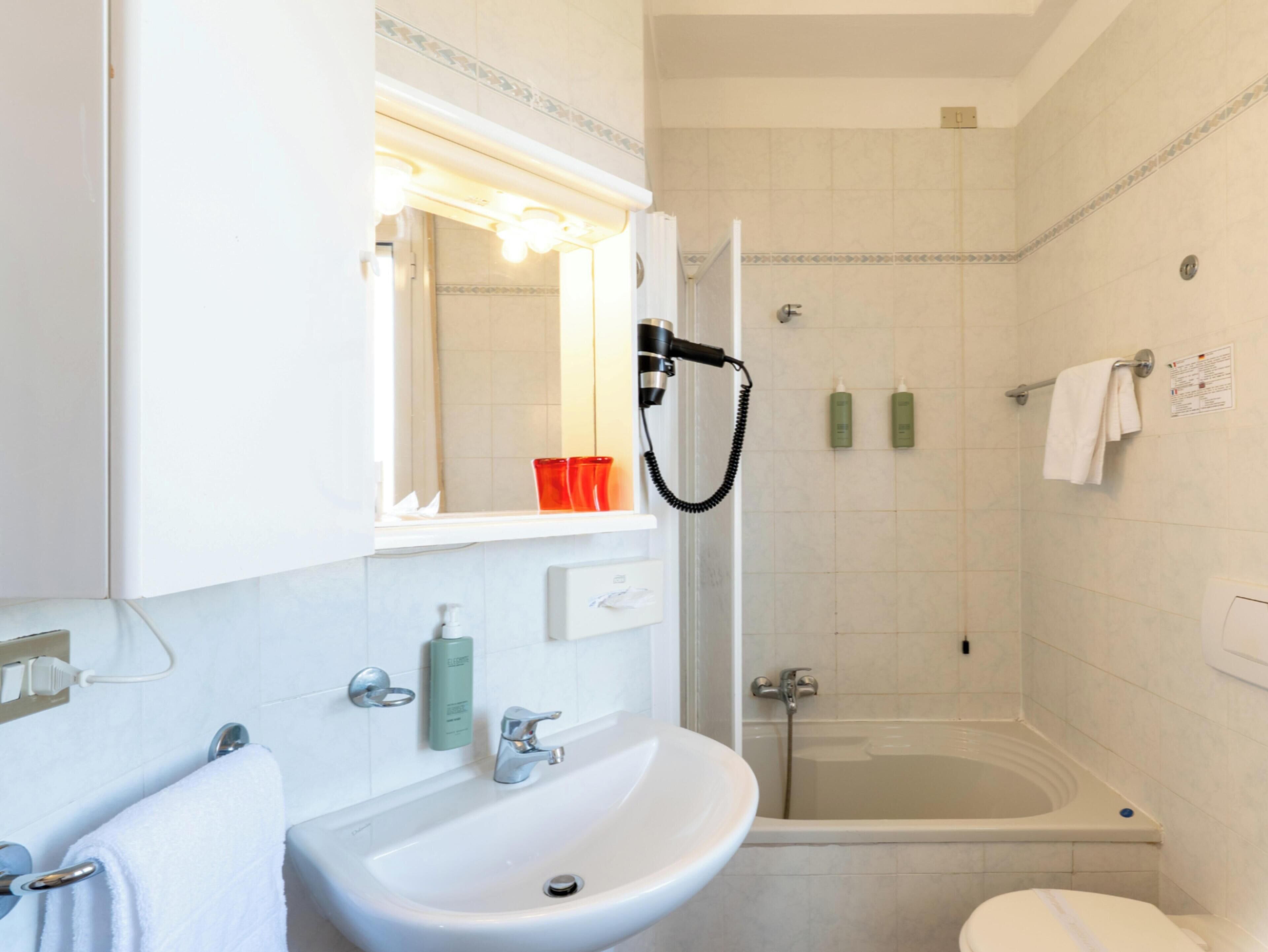 Un baño con lavamanos, espejo y zona de ducha.