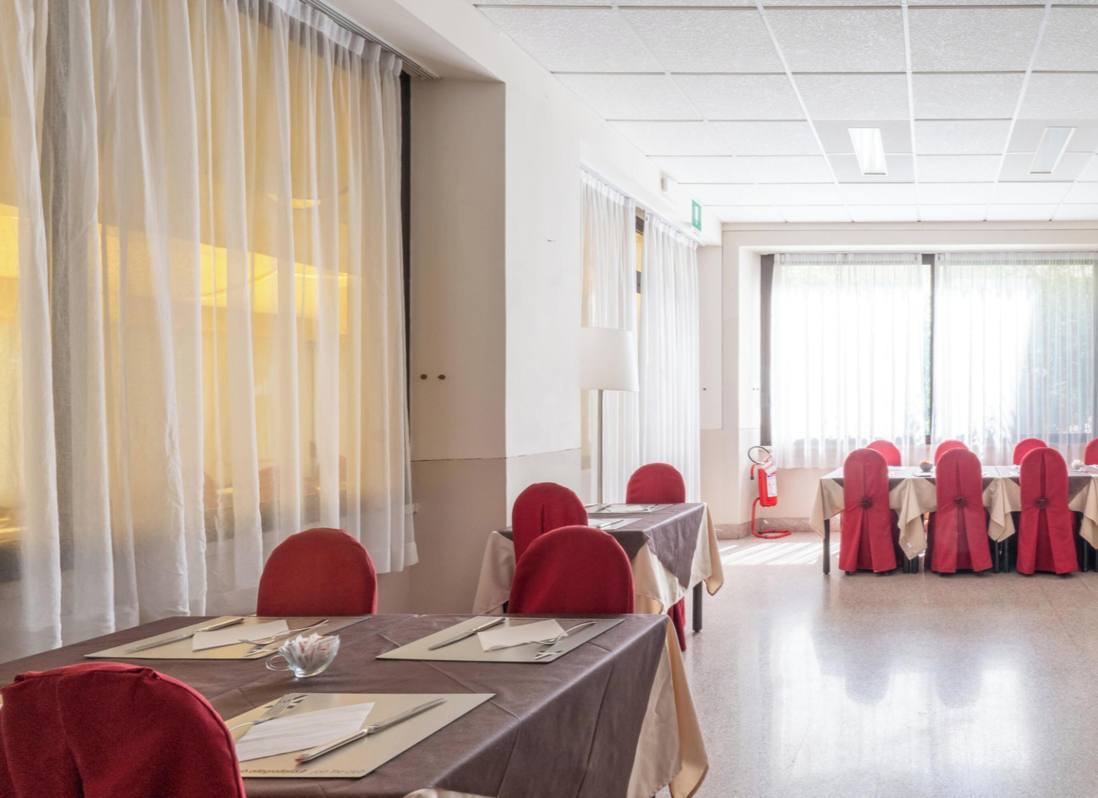 A conference room with tables set for meetings, equipped with chairs and tables, and a large window with curtains.