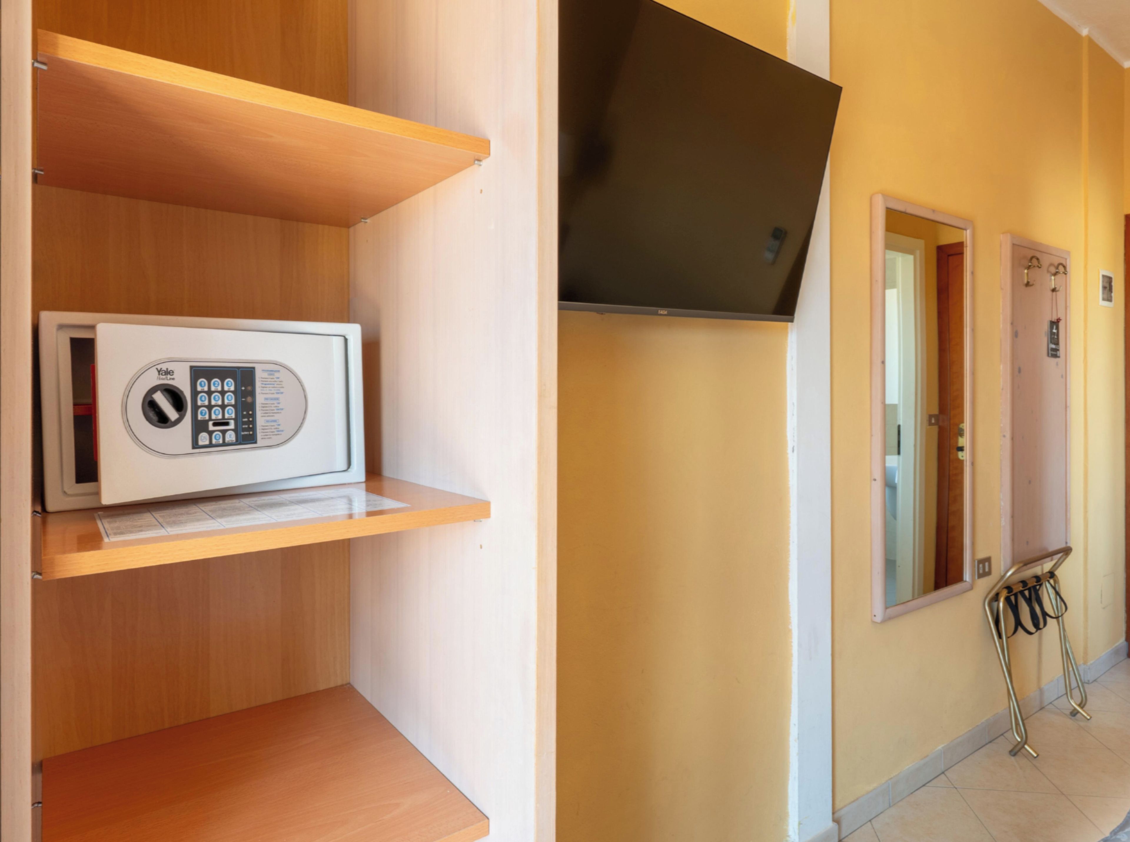 Un microondas sobre un estante de madera, una puerta con espejo y una rejilla metálica con cables.