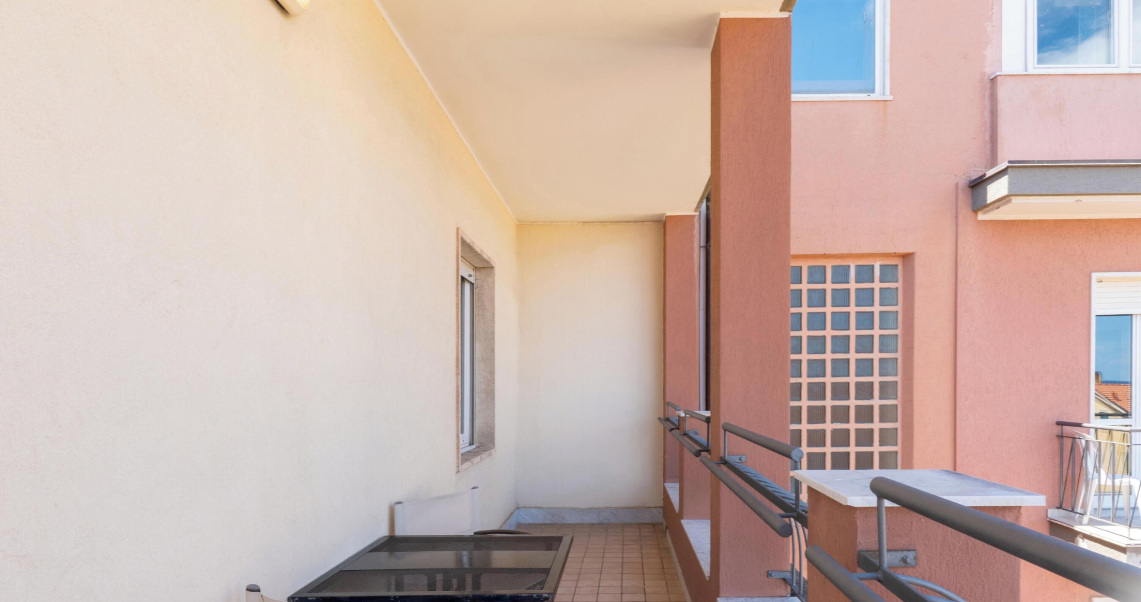 Un pasillo estrecho con una ventana a la izquierda y una puerta al final.