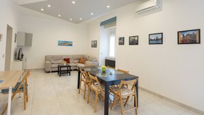 A modern living room with a dining area, featuring a sofa, a coffee table, and a dining table with chairs. - Civico 79 - Two Bedroom Apartment, Sleeps 4 (Naples)