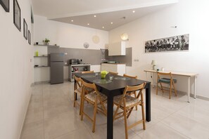 Una cocina moderna con una mesa de comedor, sillas, un refrigerador y una cafetera.