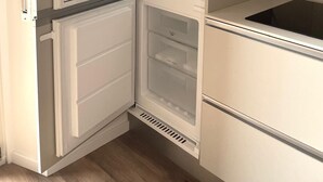 Et moderne køkken med indbygget køleskab, vask og mikrobølgeovn.