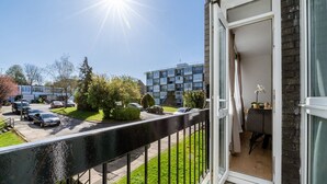 Un balcone con vista su un'area parcheggio e degli edifici.