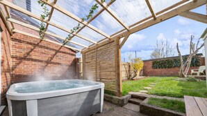 A hot tub in a covered outdoor area with a brick wall and wooden pergola. - Spacious and pet-friendly stay near New Forest (Totton)