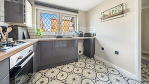 A compact kitchen with dark cabinets, a built-in oven, a gas stove, and a window with a view of buildings. - Spacious and pet-friendly stay near New Forest (Totton)