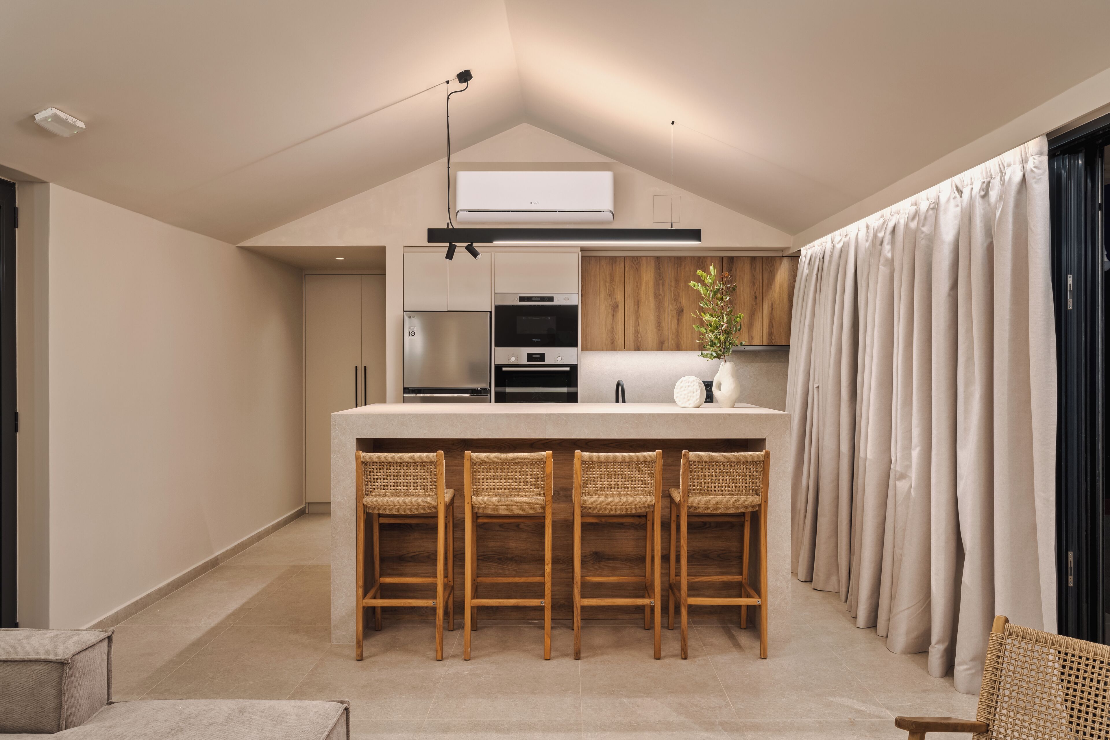 A modern kitchen with a central island, bar stools, and a built-in oven.