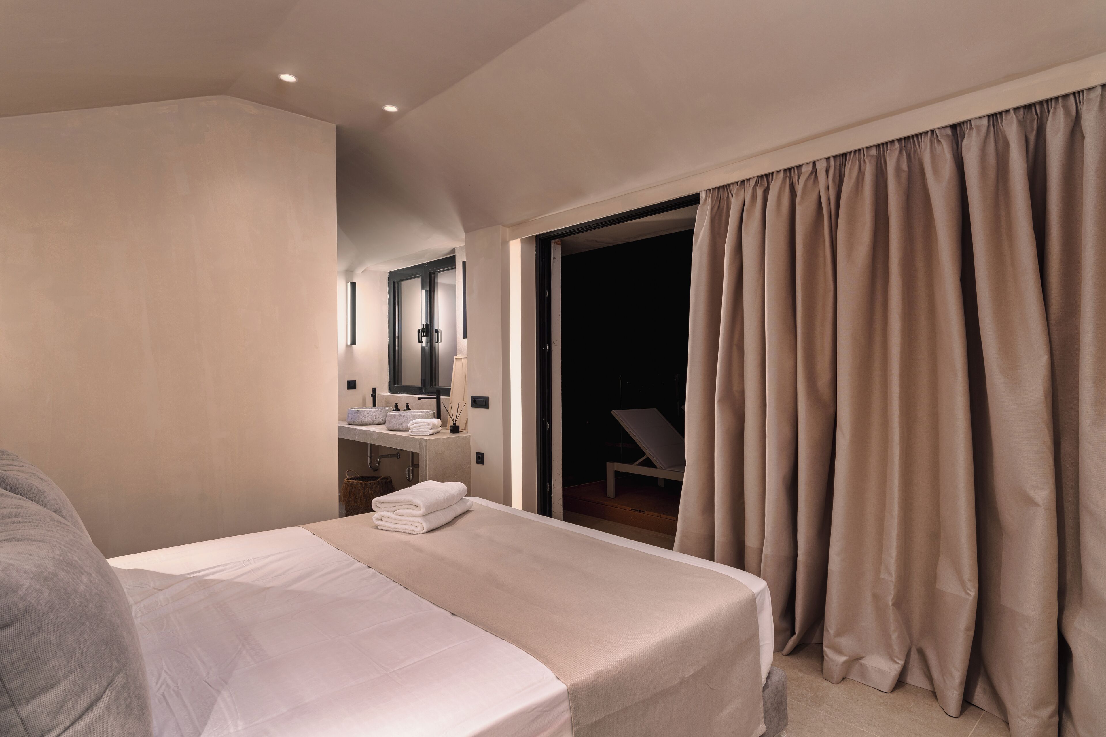 Une chambre d’hôtel moderne dotée d’un grand lit, d’une salle de bain avec un meuble-lavabo et offrant une vue sur l’extérieur.