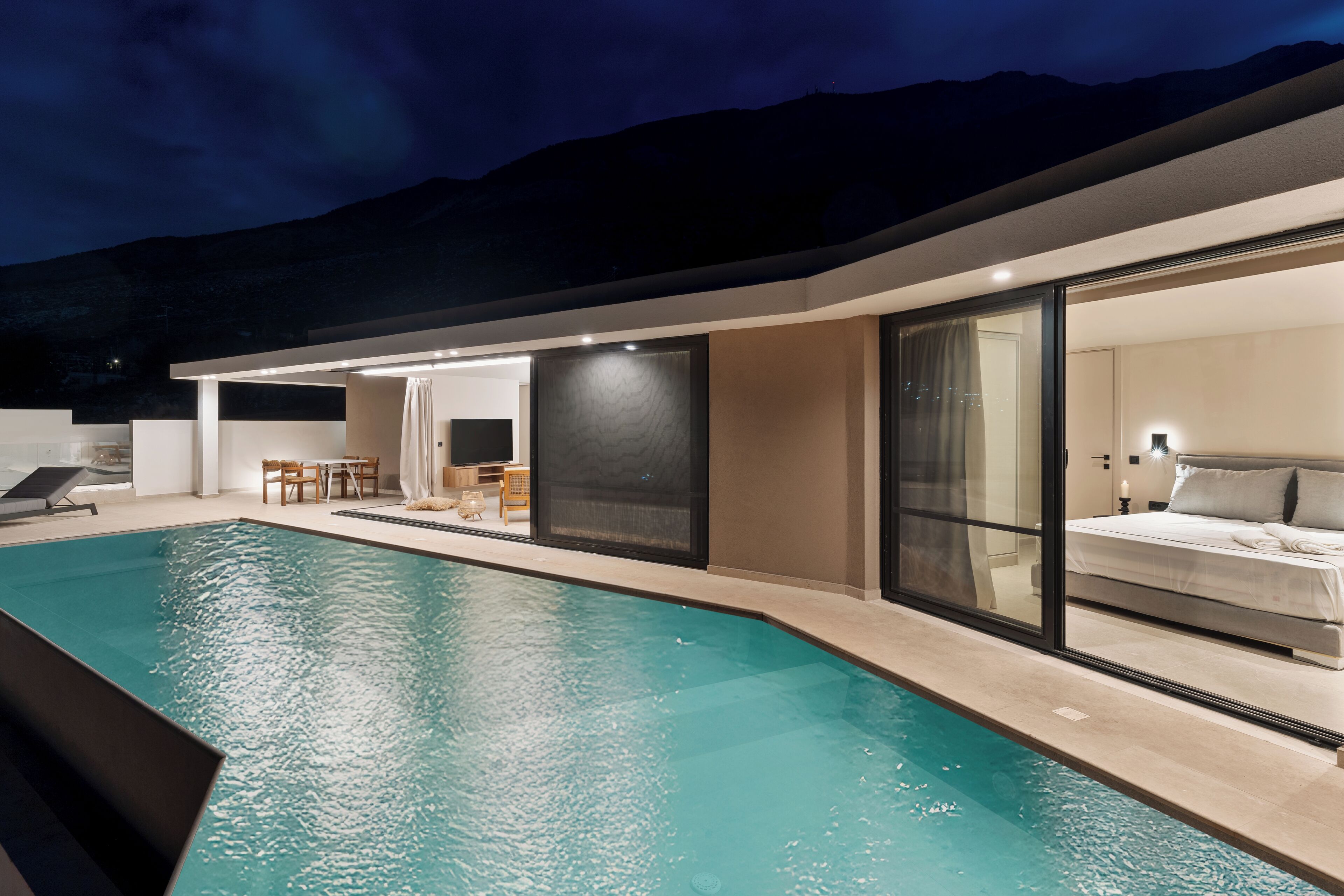 A modern hotel with a swimming pool, a dining area, and a bedroom with a large bed.