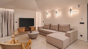 Un salon moderne avec un canapé d’angle, un téléviseur à écran plat et une table basse ronde.