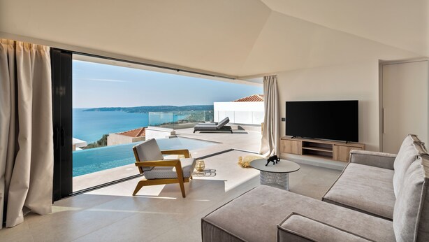 Un salon moderne doté d’un grand téléviseur, de sièges confortables et offrant une vue sur la mer.