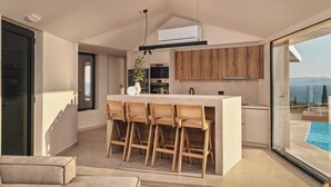 Une cuisine moderne dotée d’un îlot central, de tabourets de bar en bois et offrant une vue sur une piscine.